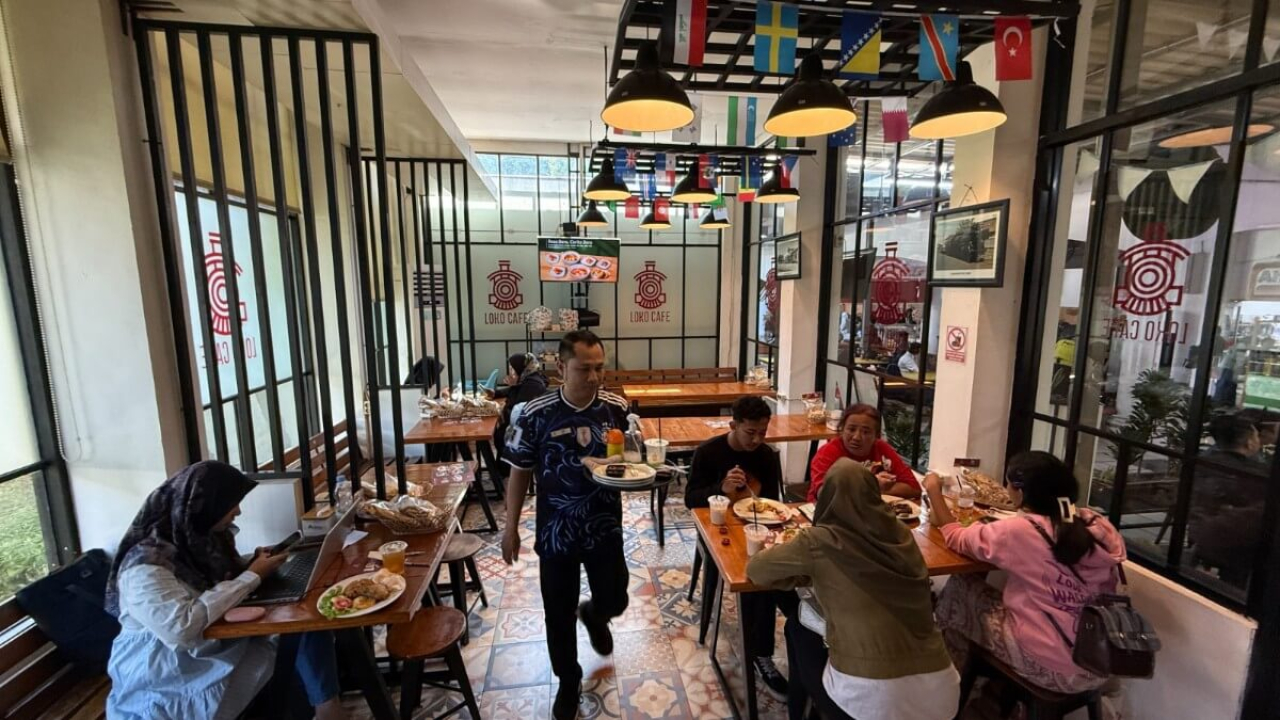 Aktivitas pengunjung di Loko Cafe Stasiun Gubeng yang menghadirkan suasana santai bagi penumpang kereta api selama libur sekolah.